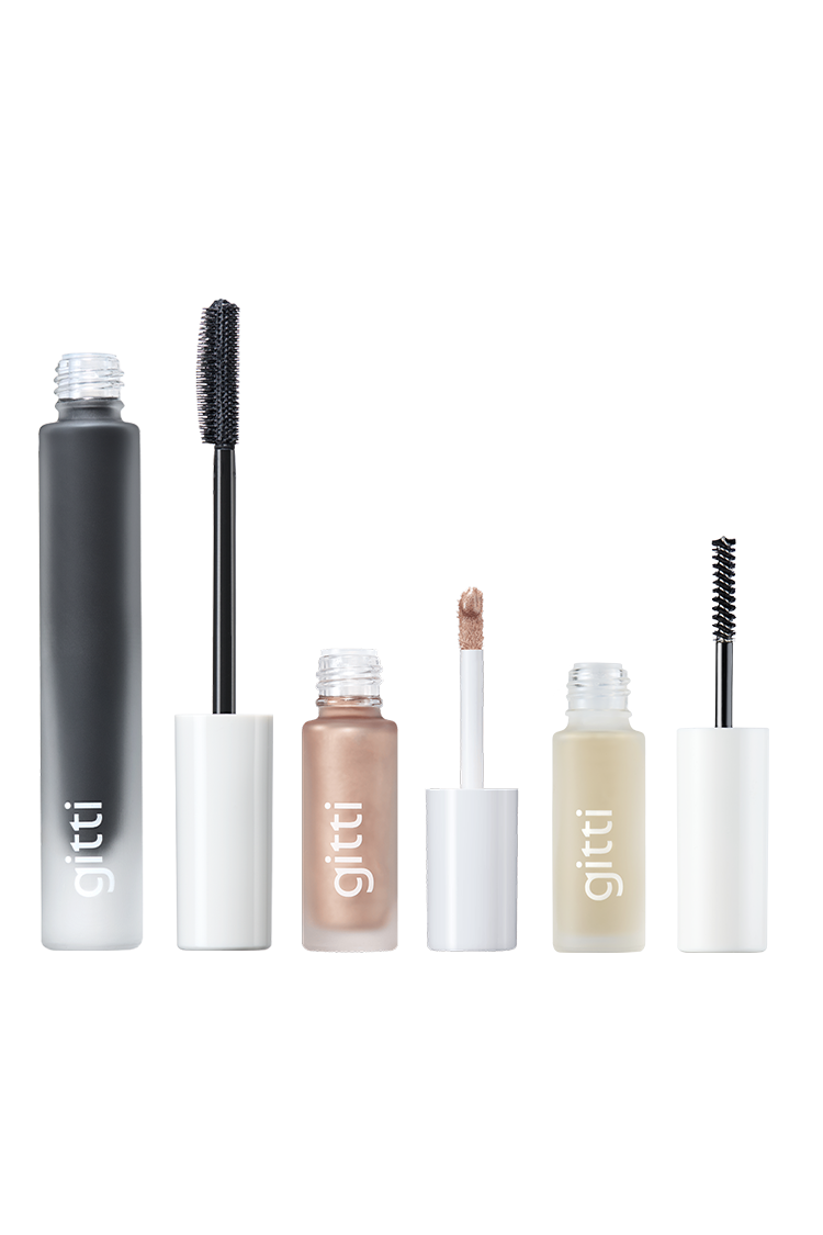 Das Signature Eye Trio - bestehend aus schwarzer Mascara, schimmerndem Halo Eyes Lidschatten mit Applikator und klarem Brow Control Gel mit Bürste - steht aufrecht auf weißem Grund.