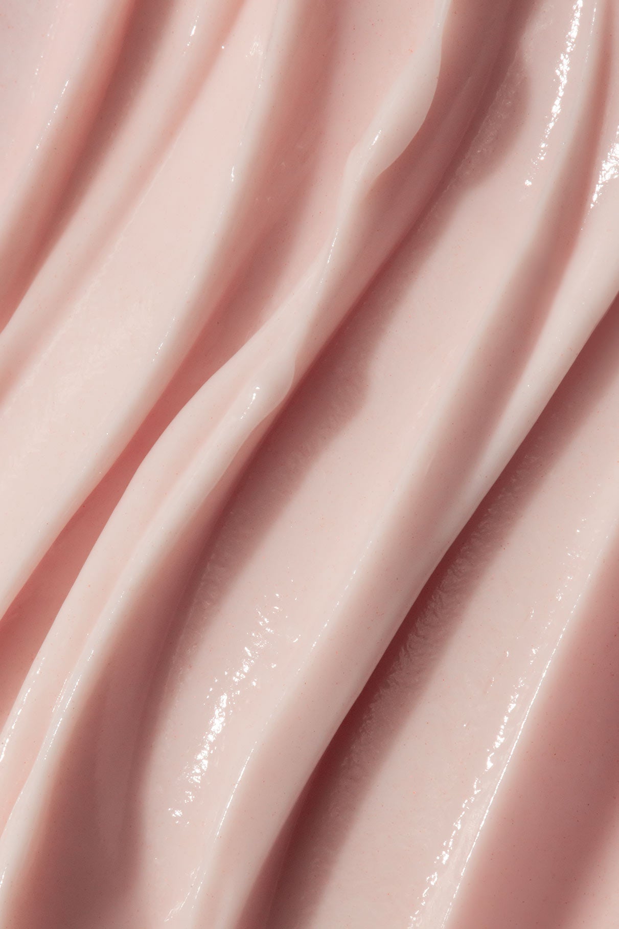 Nahaufnahme von Be A Softie, einer geschmeidigen rosafarbenen Handcreme mit glänzender, gewellter Textur, die sich perfekt mit einem pflegenden Nagelöl-Set kombinieren lässt.